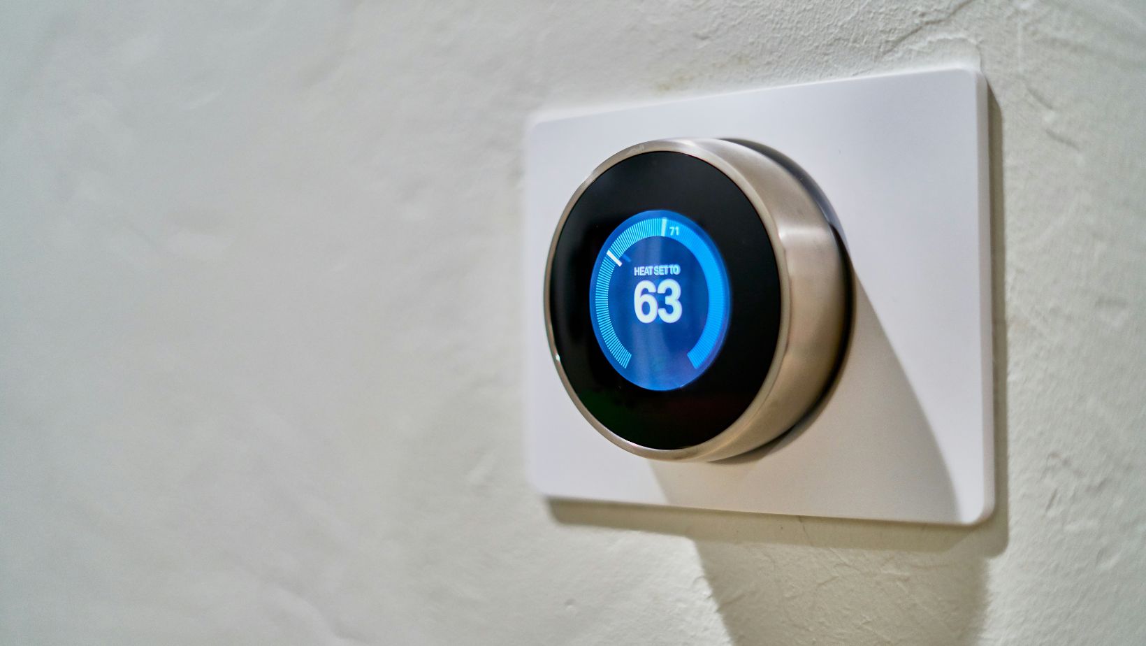 A white thermostat that shows 63 degrees